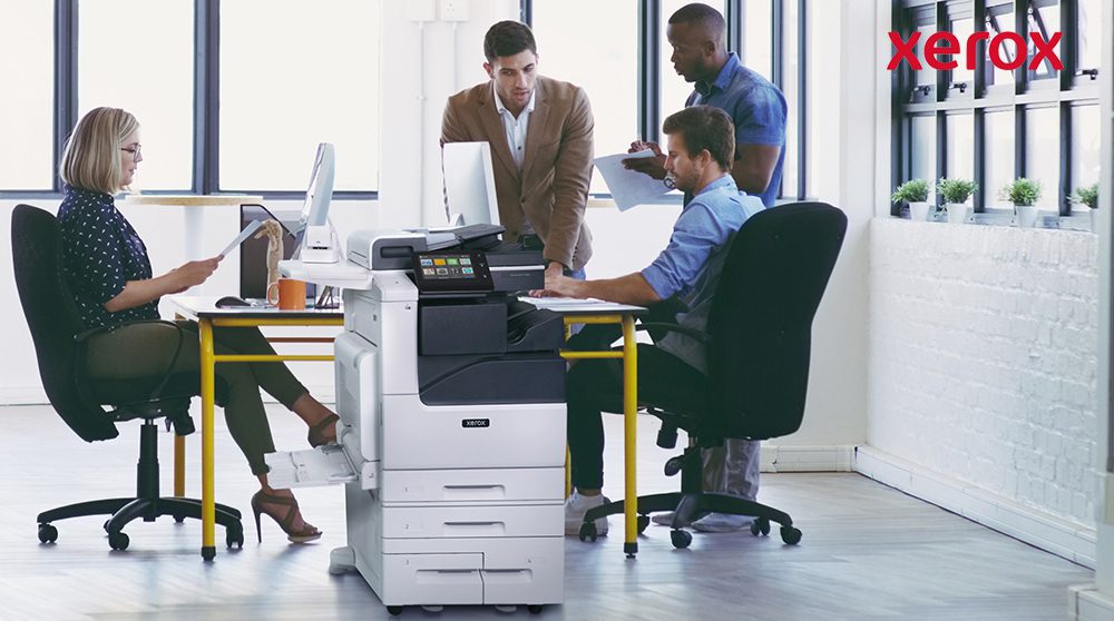 Office workers collaborating near a Xerox printer.