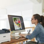 A woman seated at a desk, focused on her work, with a Xerox® C320 Colour Printer A woman seated at a desk, focused on her work, with a Xerox® C320 Colour Printer