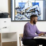 Xerox® VersaLink® C415 Colour Multifunction Printer in an office Men working on a laptop in front of a Xerox® VersaLink® C415 Colour Multifunction Printer
