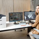 Xerox® VersaLink® C620 Printer in the workplace Woman in an office next to the Xerox® VersaLink® C620 printer
